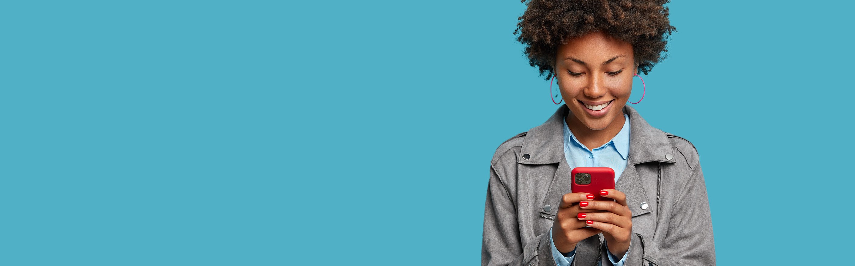 african american woman holding red cell phone standing in  front of blue background