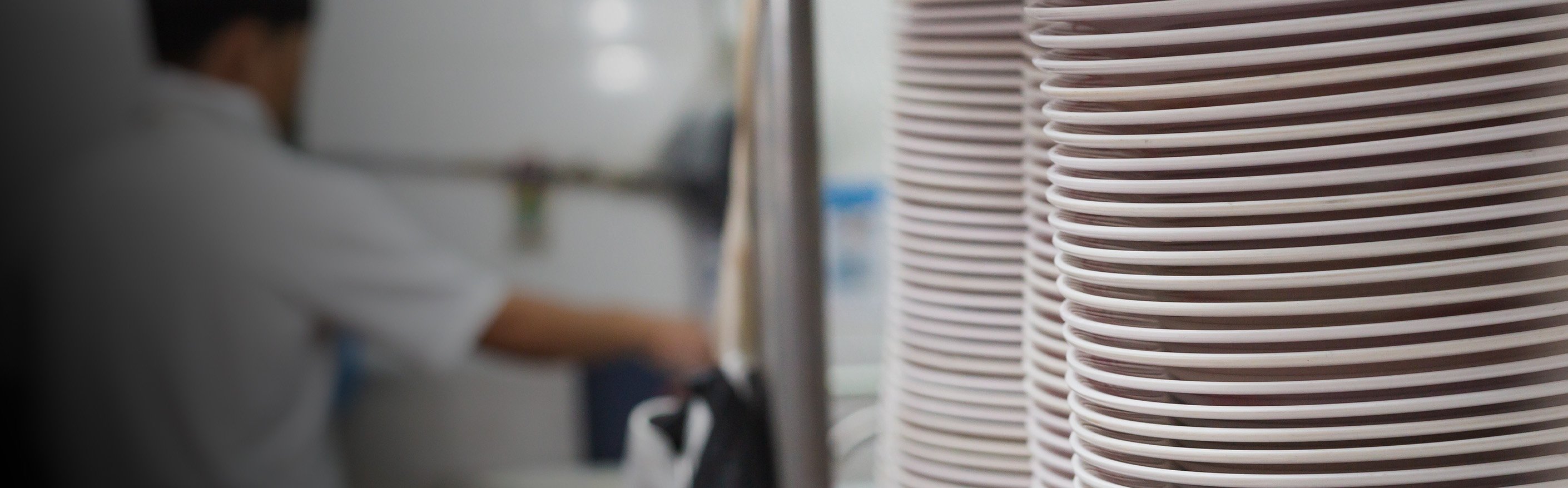 stack of dishes and person washing dishes in commercial kitchen