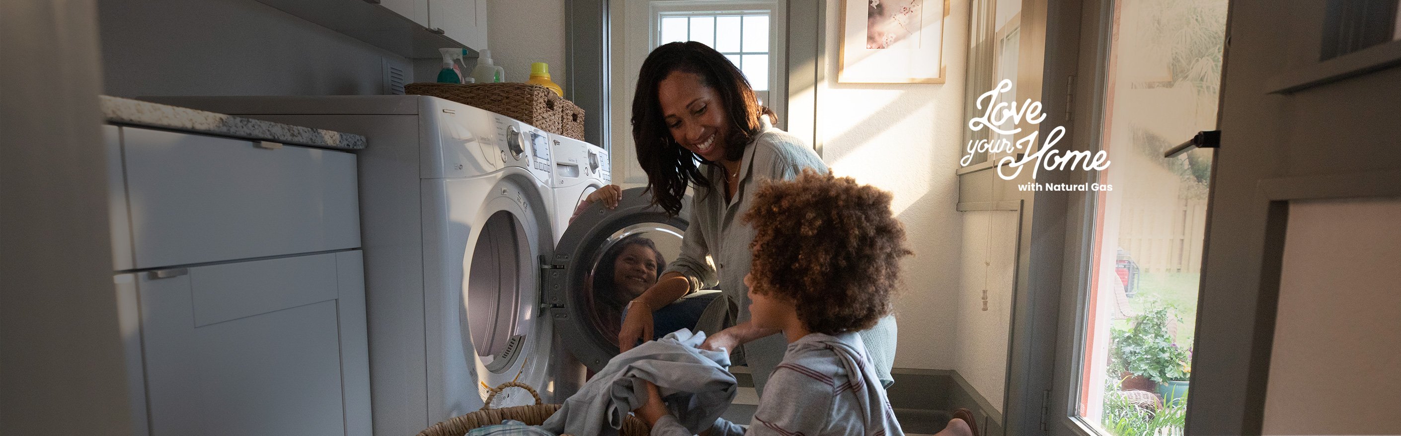 woman and child putting clothes in natural gas dryer